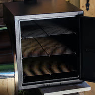 Smokebox RT-1250 & RT-700 attached to grill with door open showing the 3 shelves inside.
